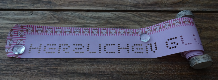 Gru?rollen mit Deko-Band auf rosa Papier mit Holz-Scheiben