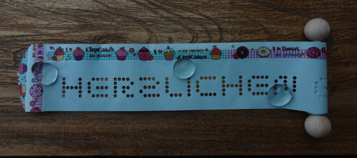 Gru?rollen mit Deko-Band auf blauem Papier mit Holz-Kugeln