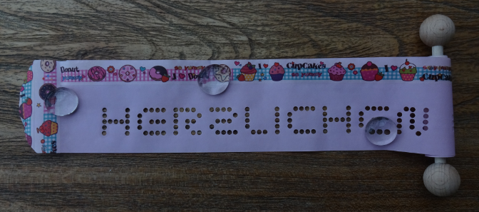 Gru?rollen mit Deko-Band auf rosa Papier mit Holz-Kugeln